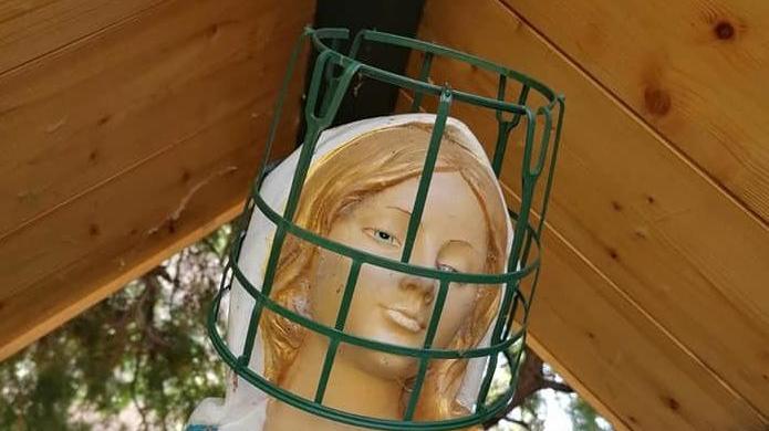 Il cestino lasciato dai vandali sulla statua della Madonna