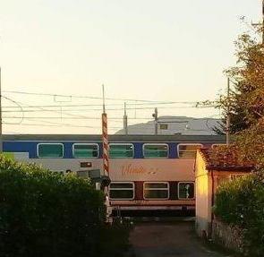 Il treno al passaggio a livello con barriere alzate a Pieve San Paolo
