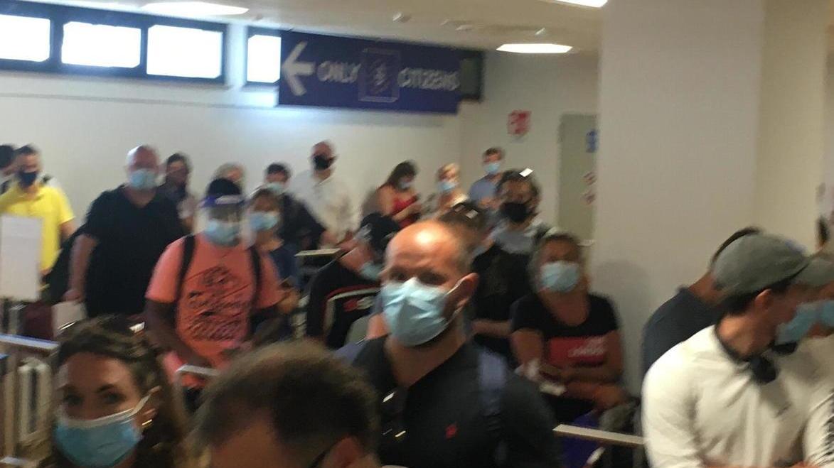 In fila a distanza ravvicinata per far controllare i passaporti