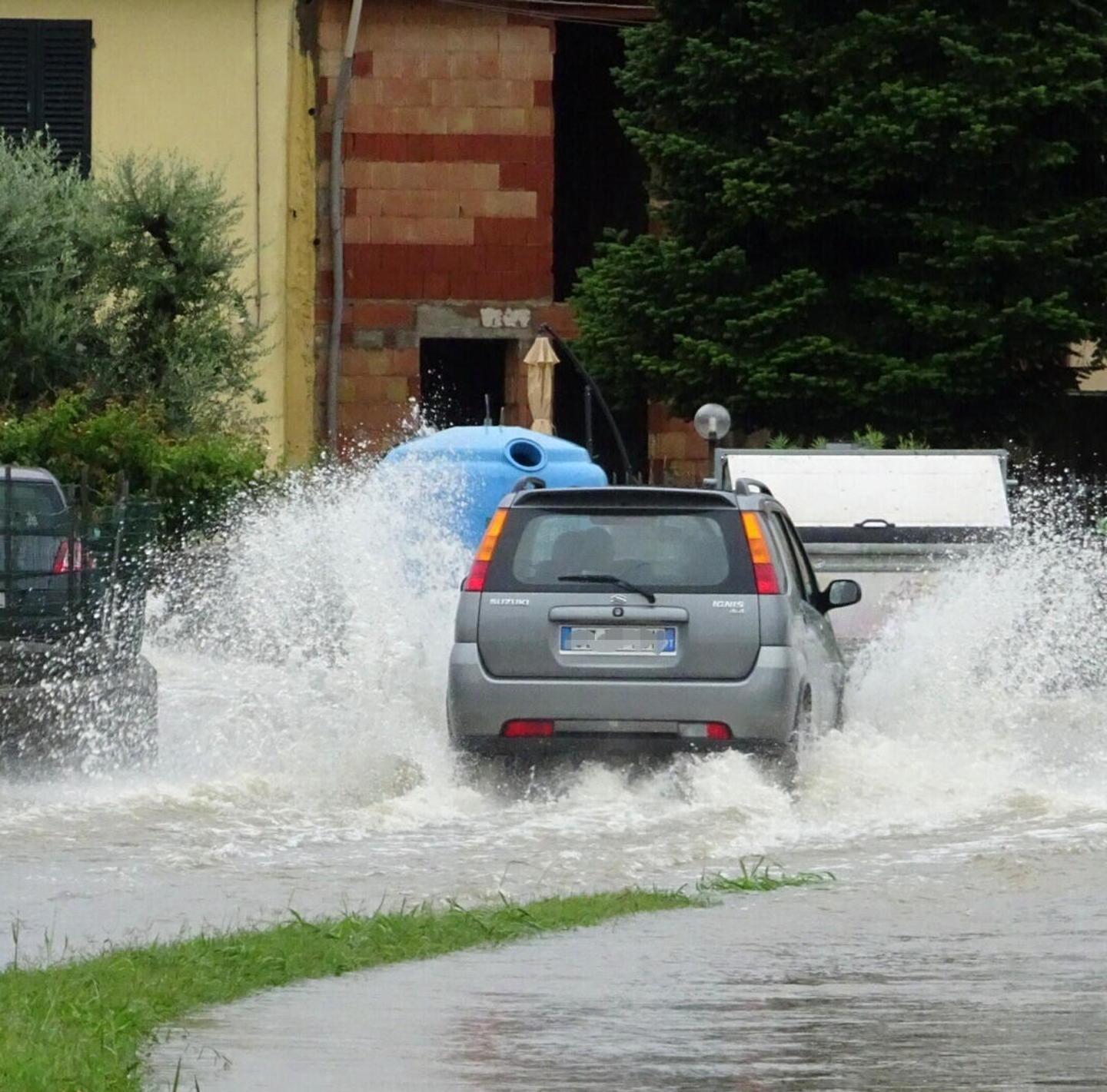 Un'auto si fa strada in un fiume d'acqua piovana