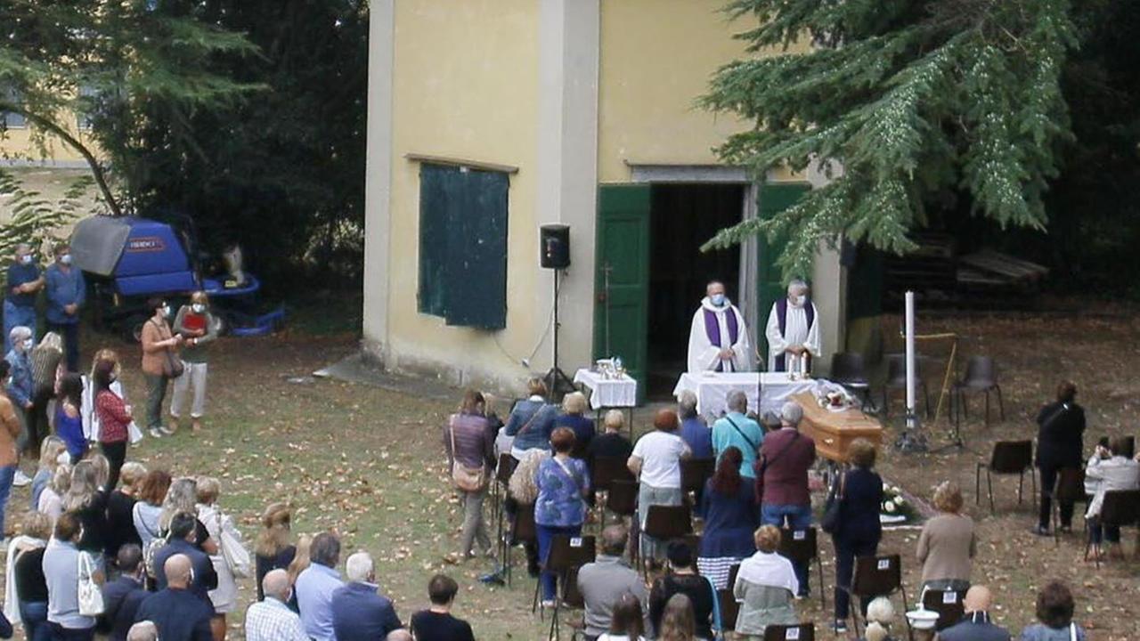 Il feretro nel giardino della chiesa di Coltano e i due officianti, don Andrea Antonelli e don Emanuele Morelli