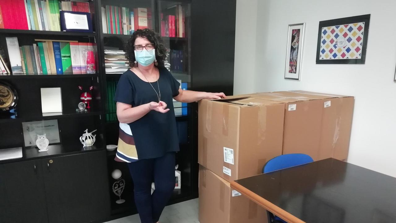 La preside Maria Grazia Ciambellotti accanto agli scatoloni di mascherine appena arrivate