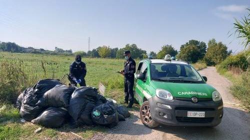 I carabinieri forestali alle prese con alcuni grossi sacchi neri, solo una piccola parte della discarica abusiva di Paperino