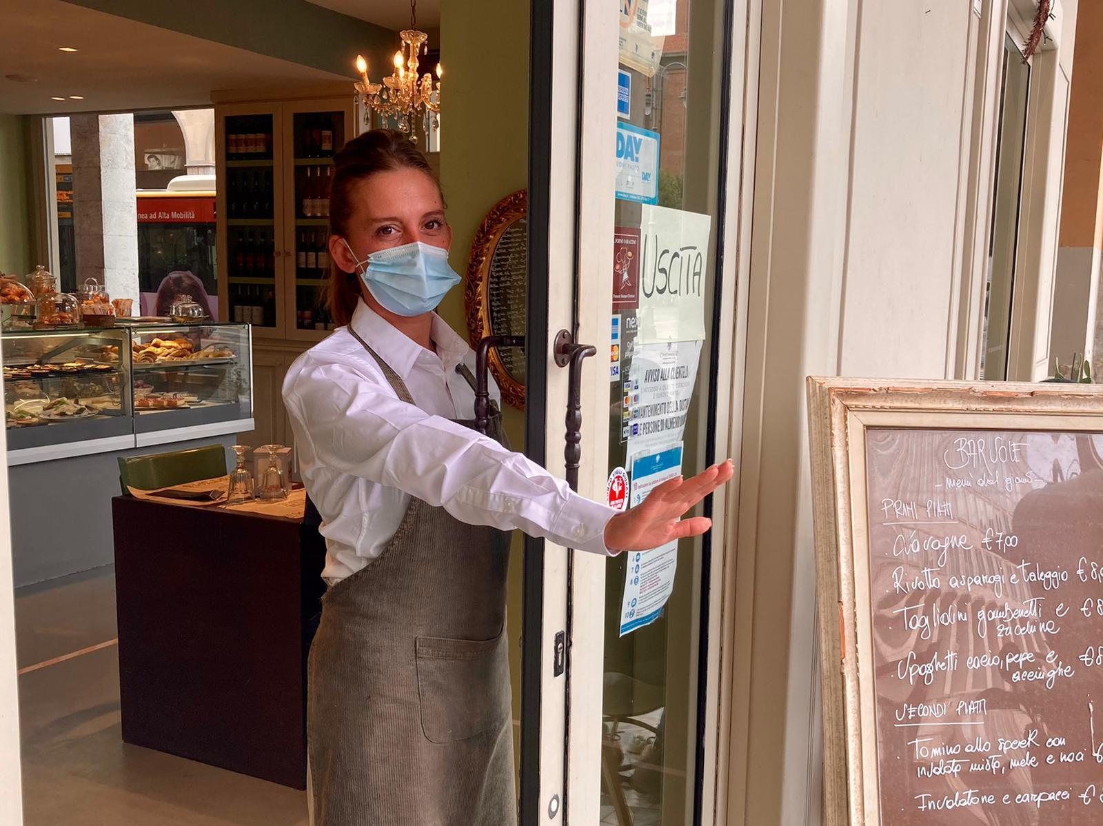 La porta "chiusa" del bar Sole con una dipendente che mostra come la vetrata non vi sia più (foto Dario Marzi)