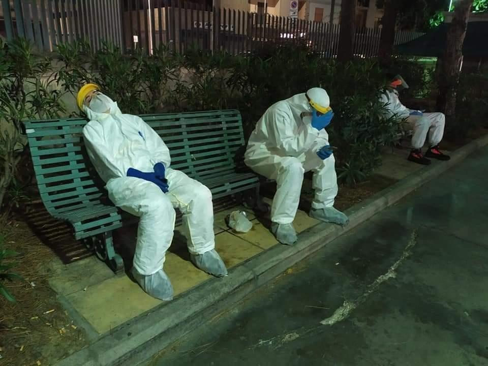 Volontari stremati si riposano sulle panchine all'esterno del Santissima Trinità di Cagliari