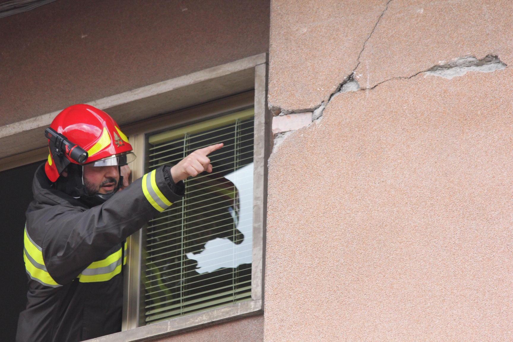 Un vigile del fuoco mostra una grossa crepa sull'esterno di un'abitazione, è il 9 dicembre 2019