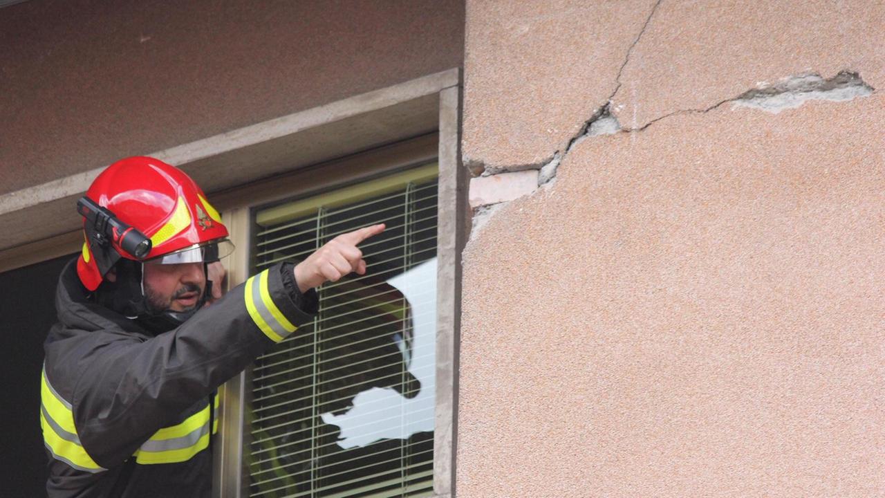 Un vigile del fuoco mostra una grossa crepa sull'esterno di un'abitazione, è il 9 dicembre 2019