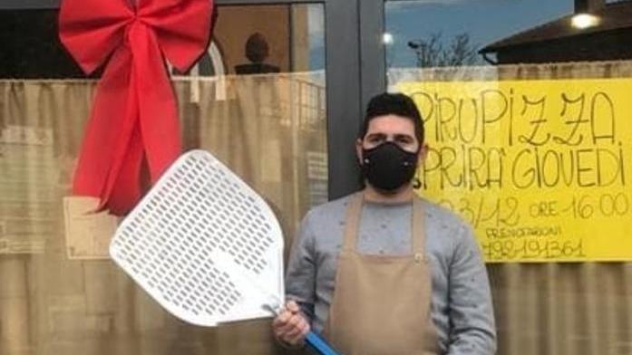 Leonardo Calamusa di fronte al suo locale con la pala da pizzaiolo e il fiocco rosa per la nascita della figlia