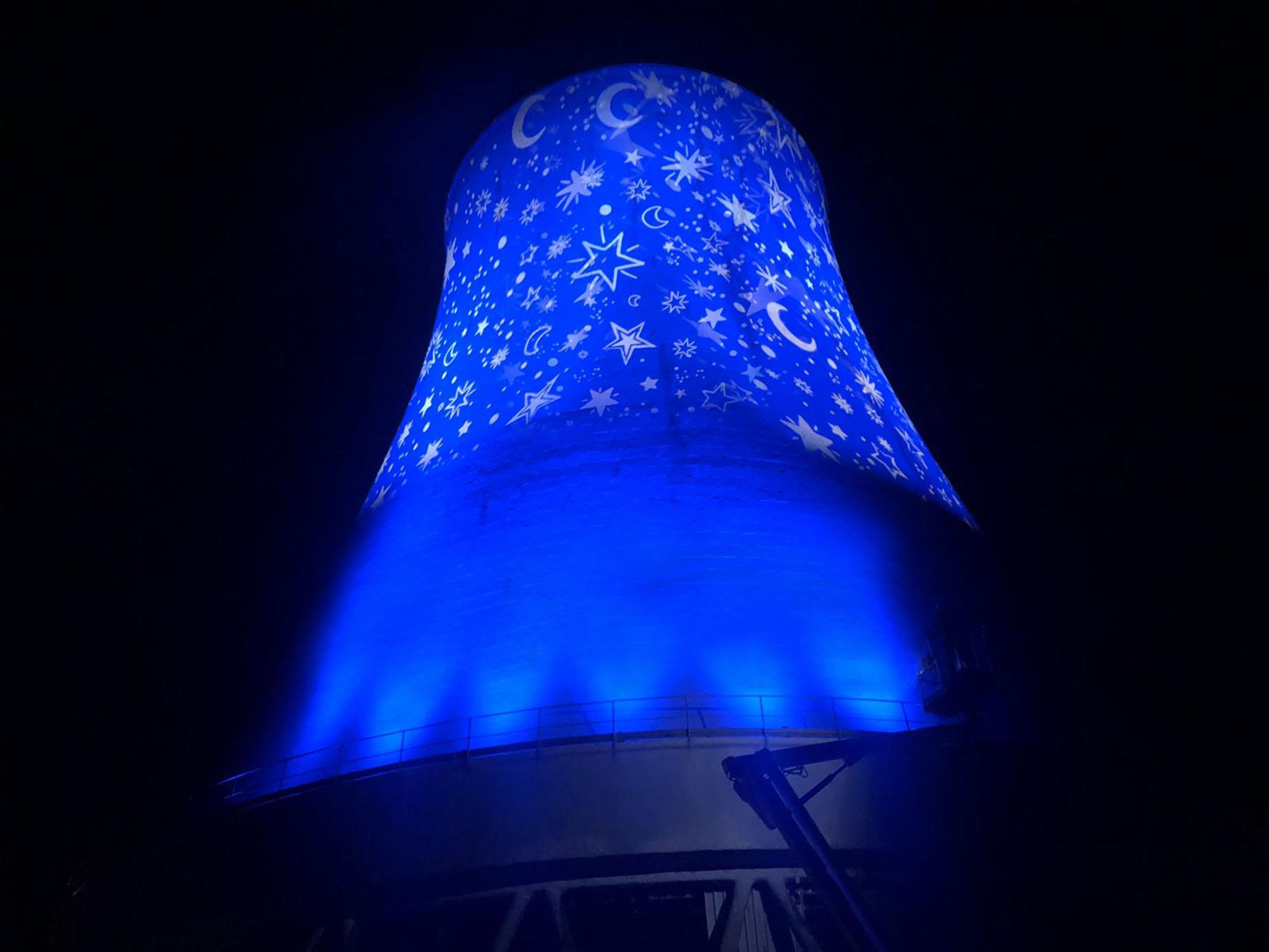 La torre refrigerante della centrale geotermica di Monterotondo Marittimo si accende di un elegantissimo manto di stelle e lune su sfondo blu