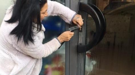 La commerciante mentre cerca di aprire la porta