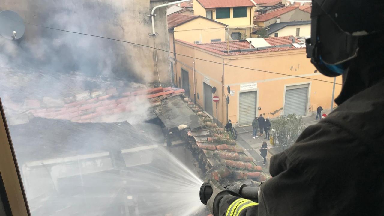 Un vigile del fuoco getta acqua da una palazzina a fianco a quella della mansarda incendiata