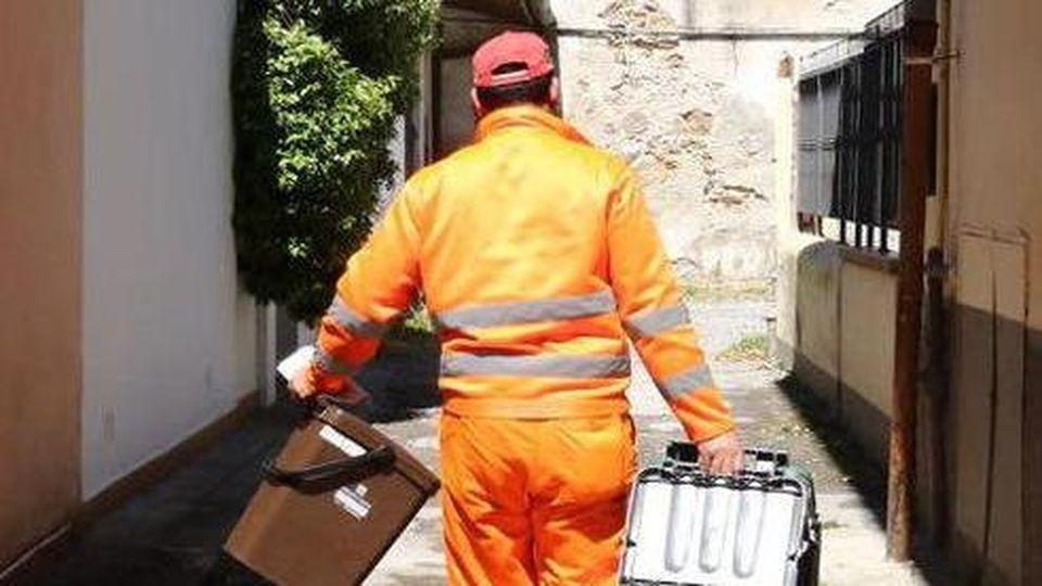 Un operatore con due bidoni della raccolta differenziata (foto d’archivio)
