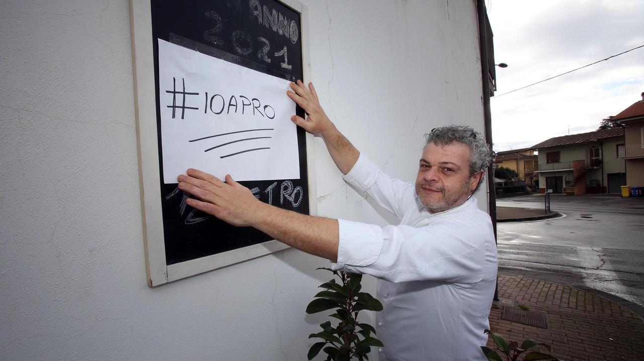 Enrico Nistri appende il cartello con la scritta “#Ioapro” davanti alla Lanterna Blu