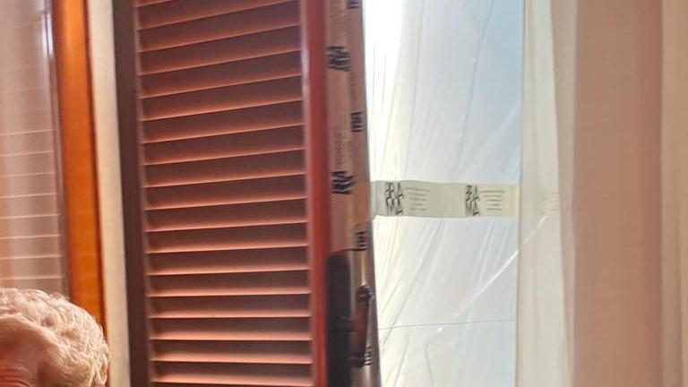La pensionata 88enne Licia Daini mentre fa vedere la finestra e la persiana forzate dai ladri per entrare in casa