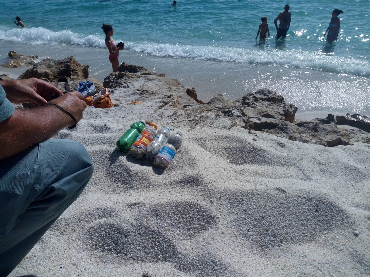 Bottiglie con sabbia portata via da una spiaggia, immagine di repertorio