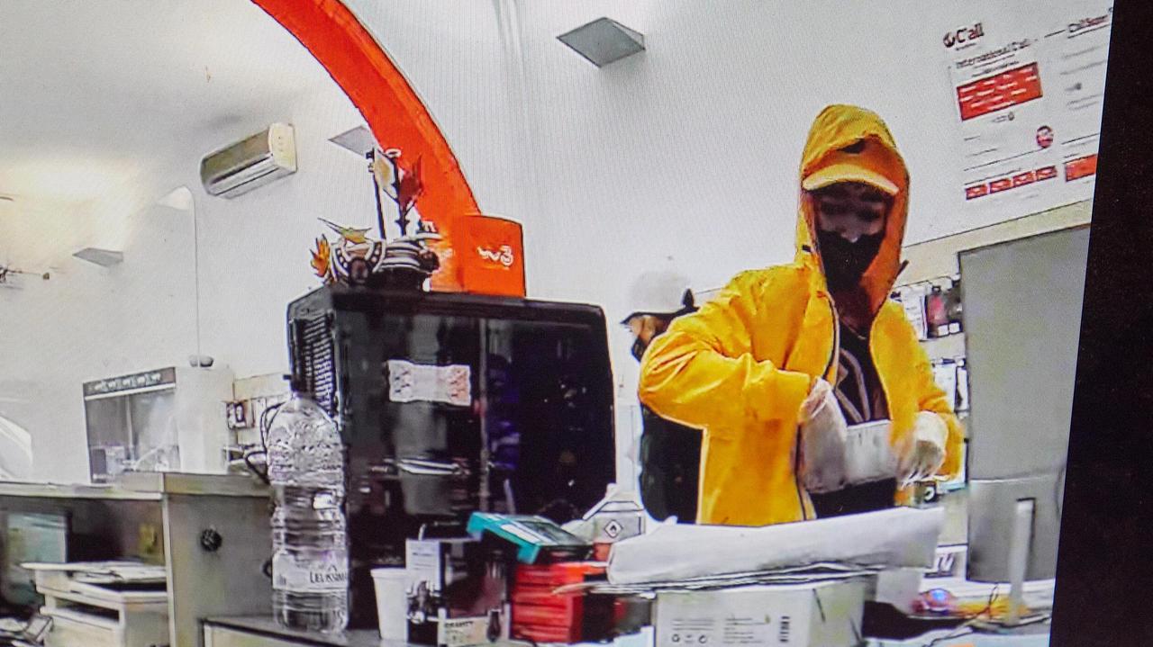 Uno dei rapinatori all'interno del negozio di telefonia "Digital Point" di Empoli (foto Carlo Sestini)