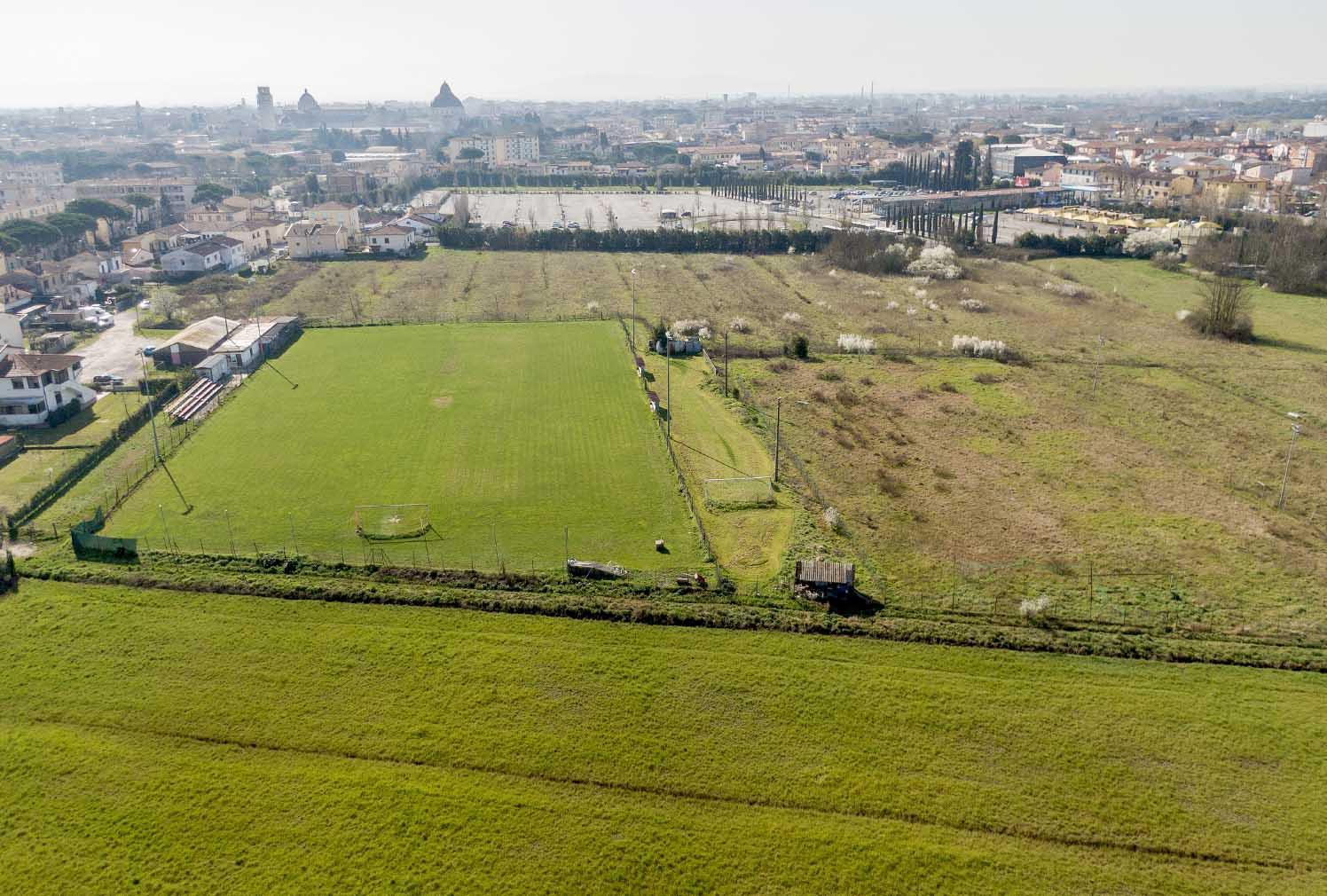 Dal drone l’area della nuova cittadella dello sport: sono i campi incolti a destra dell’impianto della Bellani, sullo sfondo il parcheggio di via Pietrasantina e piazza dei Miracoli