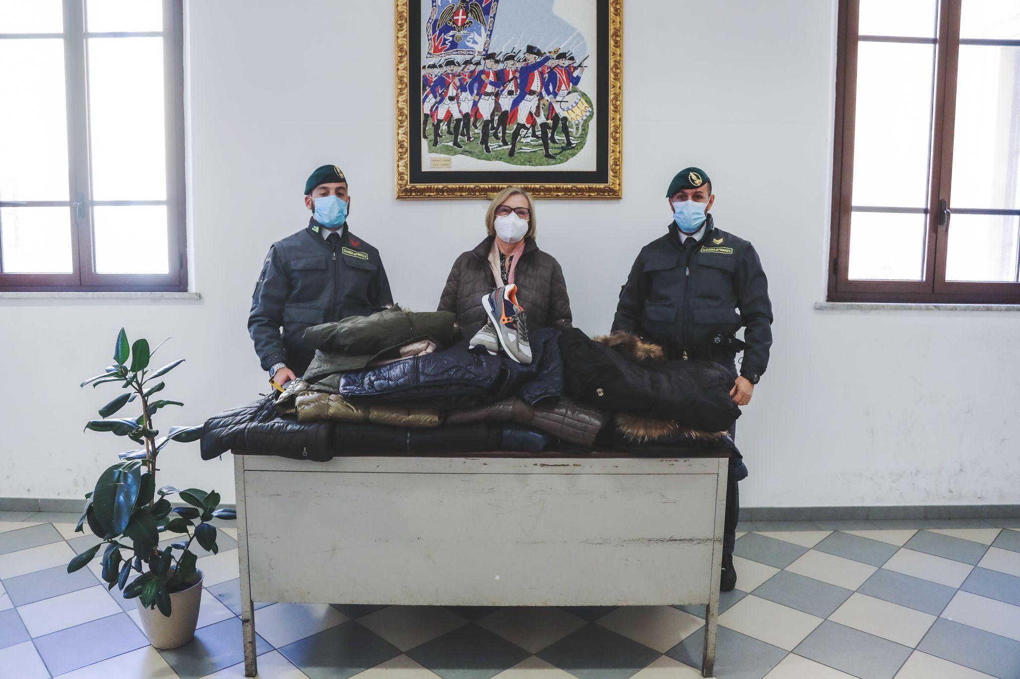 Due finanzieri e al centro la presidente della cooperativa, Stella Angelini, con la merce donata (foto Dario Marzi)