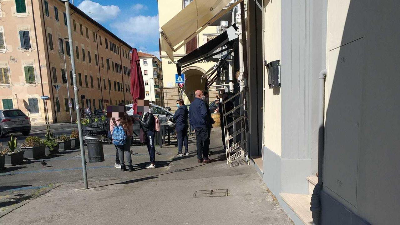 Il ragazzino e l'adulto, insieme ad altre persone, in coda in piazza Damiano Chiesa