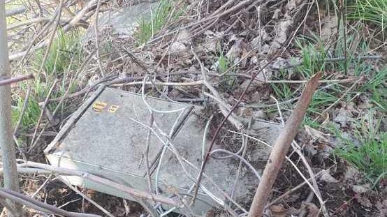 Scatola di telefonia e cavi abbandonati sull’erba