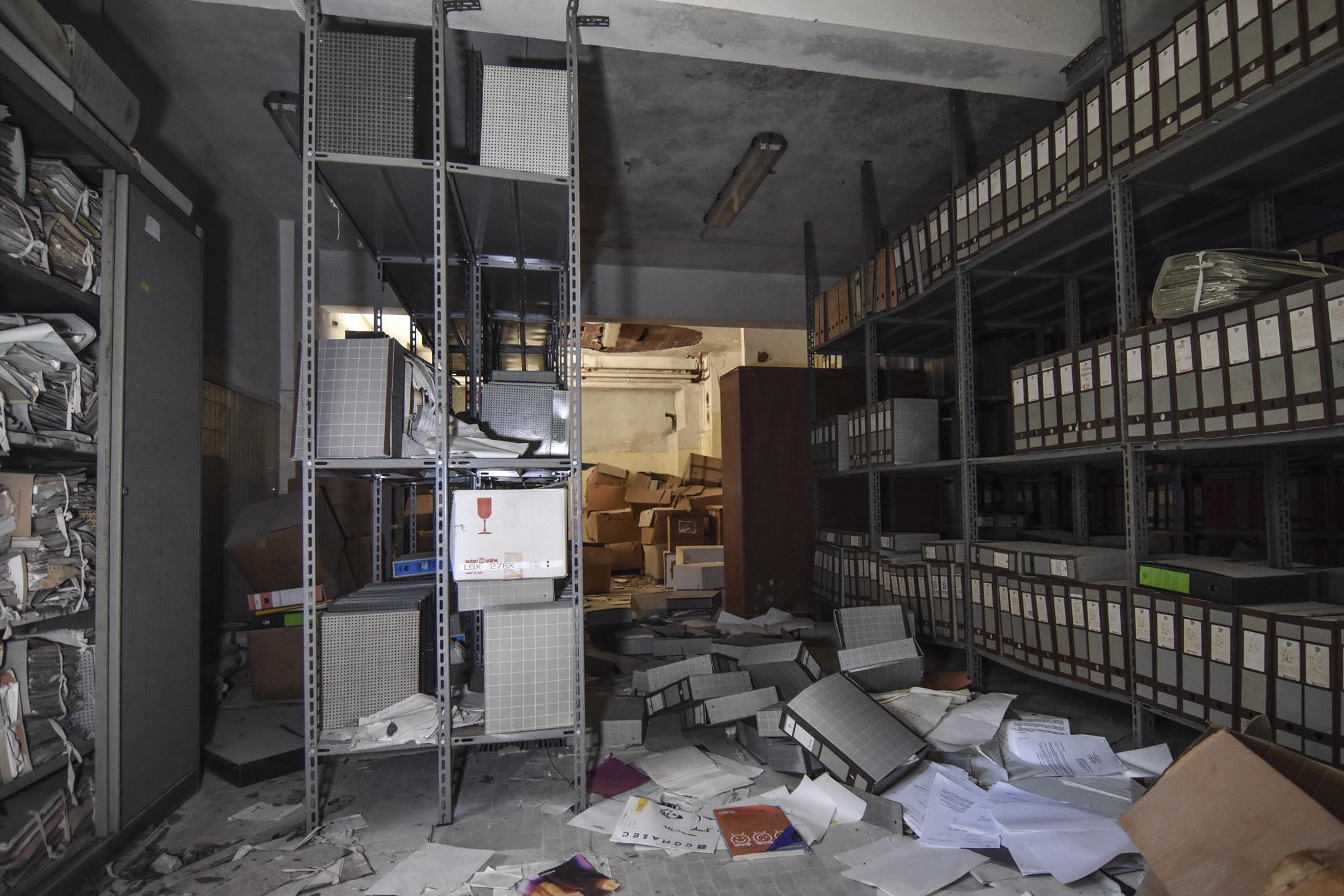 Una delle stanze-archivio abbandonate, con scaffalature zeppe di documenti e scatoloni ancora pieni di materiale