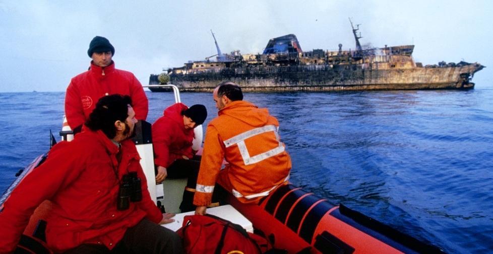 Una squadra dei vigili del fuoco, a bordo di un gommone, la mattina dopo la sciagura davanti al relitto del Moby Prinbce annerito dal rogo