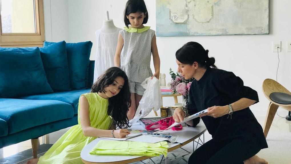 La stilista Emanuela Nurra, a destra, disegna gli abiti sotto lo sguardo attento delle figlie Emilia e Giulia