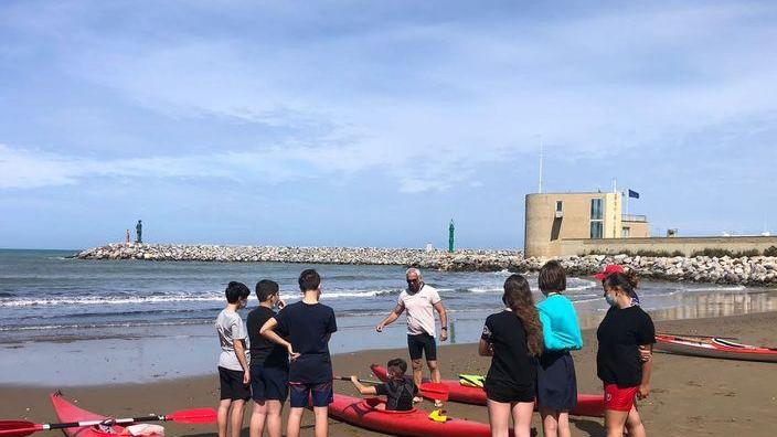 Gli studenti della scuola media in spiaggia a lezione di kayak