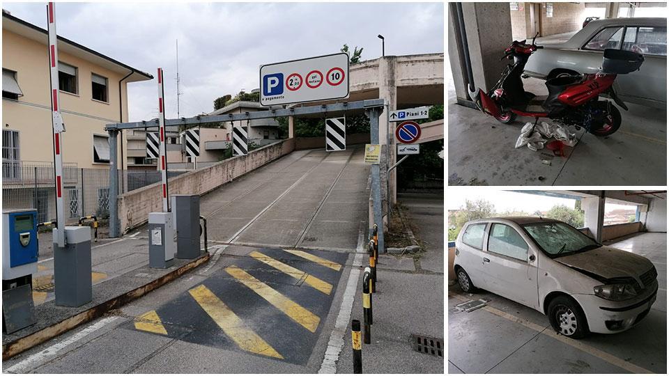 la rampa di accesso (con sbarra perennemente alzata) ai parcheggi per le auto; a fianco uno scooter "cannibalizzato" con il furto di vari pezzi e un’auto a cui hanno sfondato il parabrezza