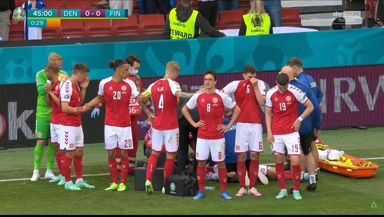 Eriksen a terra circondato dai suoi compagi di squadra