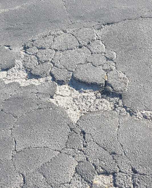Una strada piena di buche ormai abbandonata da tutti 