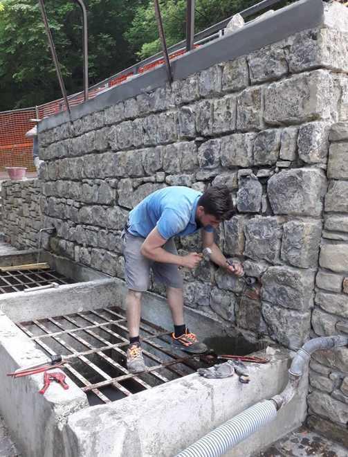 Un operaio al lavoro per il recupero della fontana di Barazzone