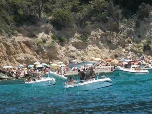 Spiaggia pienissima di vacanzieri e decine di barche a poca distanza