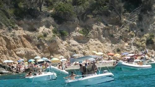 Spiaggia pienissima di vacanzieri e decine di barche a poca distanza