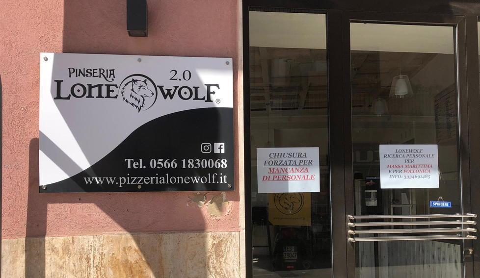 Il cartello per la ricerca di personale sulla porta della pizzeria follonichese