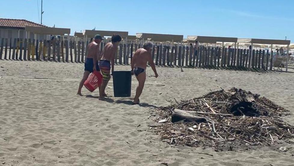Alcuni bagnanti puliscono la spiaggia libera tra il bagno Beretta e il bagno Beppe