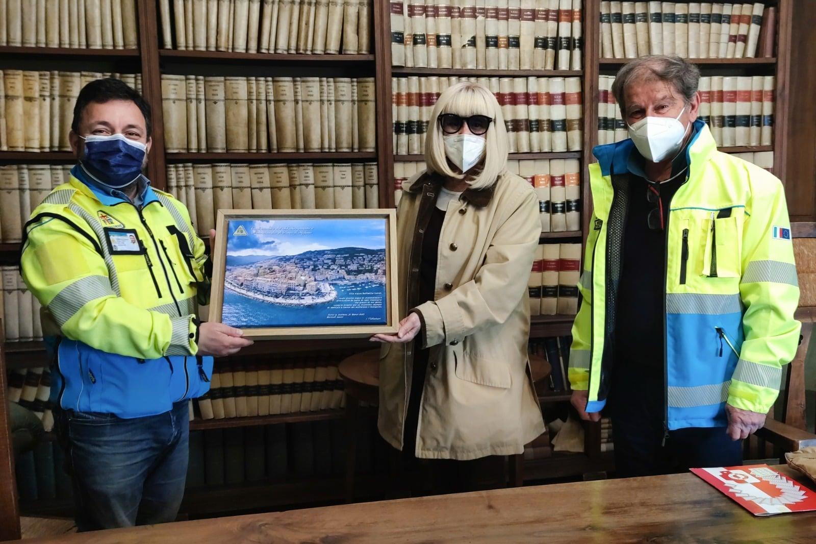 Raffaella Carrà durante l'incontro in occasione della donazione della palestra, mentre riceve in regalo una foto panoramica di Porto Santo Stefano