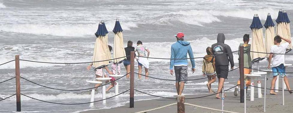 Spiaggia flagellata e ombrelloni in mare