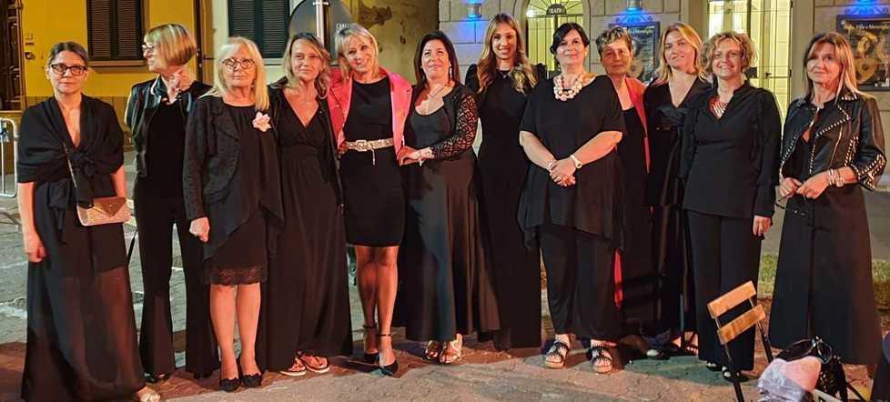 Abiti scuri e tovaglie nere con dettagli in rosa per la cena in piazza