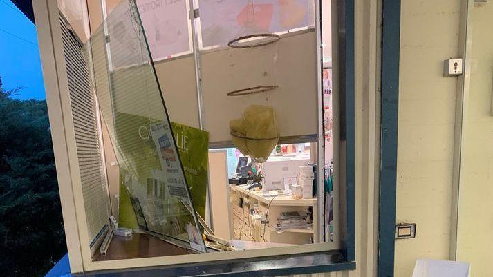 Distrugge con un tombino la vetrata della farmacia