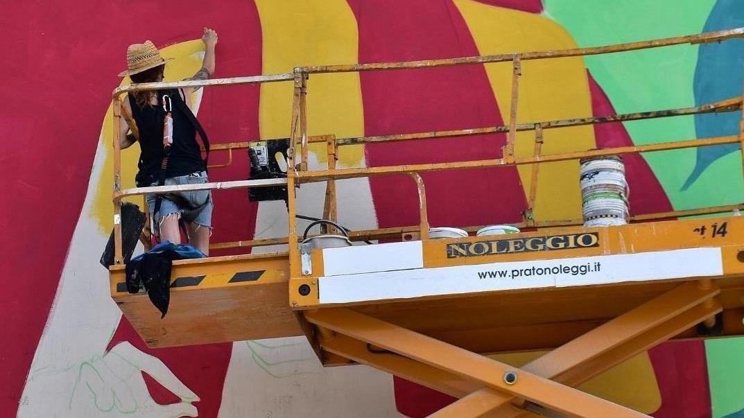 Un'artista impegnata a disegnare una delle quattro opere sulla torre Enel