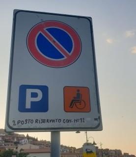 Stallo per disabili con cartello scritto a penna 