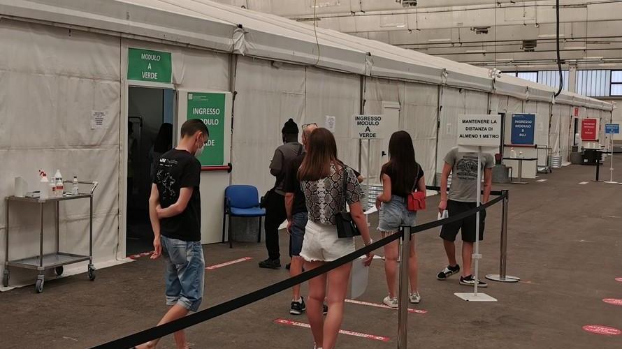 Alcuni ragazzi e i loro genitori in fila dentro al padiglione vaccinale delle Fiere di Mancasale (foto di repertorio)