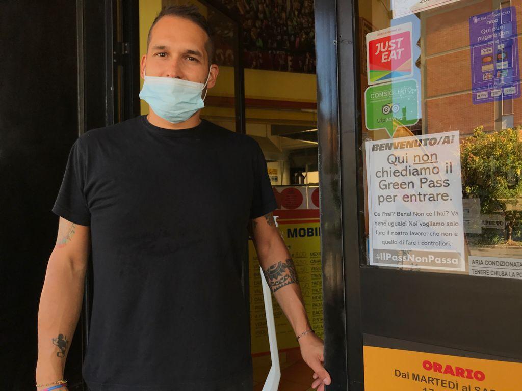 Daniele Casagrande all'ingresso della sua pizzeria: sulla destra è visibile il cartello anti-Green pass