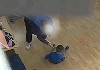 Una delle immagini della polizia: si vede una maestra che avvicina la mano “aperta” al volto di un bimbo