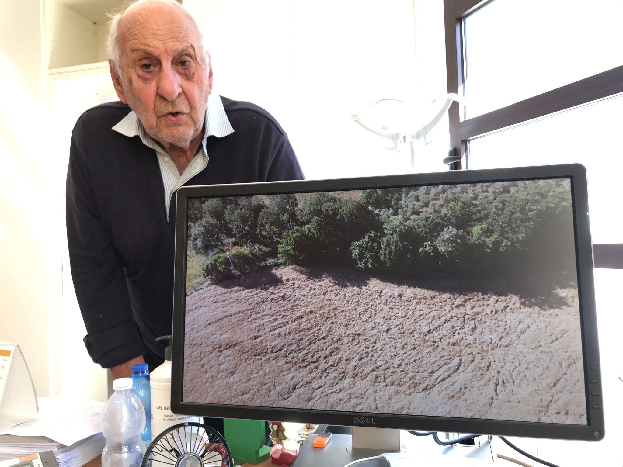 Adalberto Suardi mentre mostra una foto che testimonia i danni fatti dai cinghiali alle sue coltivazioni