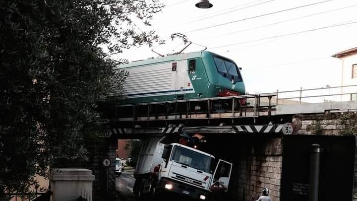 Il camion incastrato sotto il sottopasso mentre transita un treno a Narnali