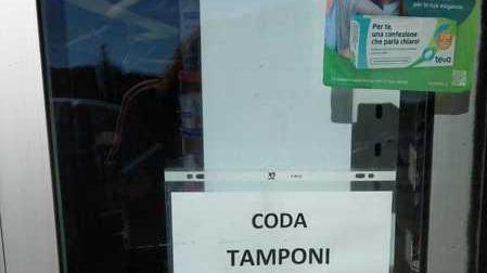 Un cartello che indica la "coda per i tamponi" all'ingresso di una farmacia di Pisa