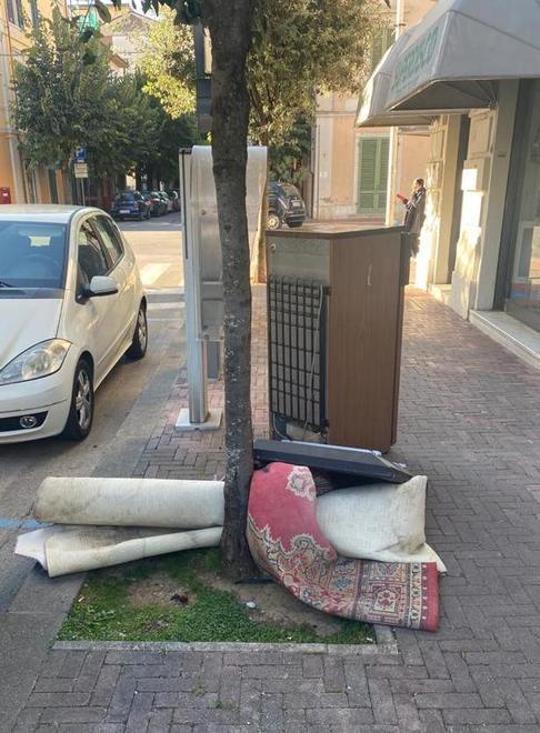 Tappeti e stufa abbandonati sul marciapiede in pieno centro
