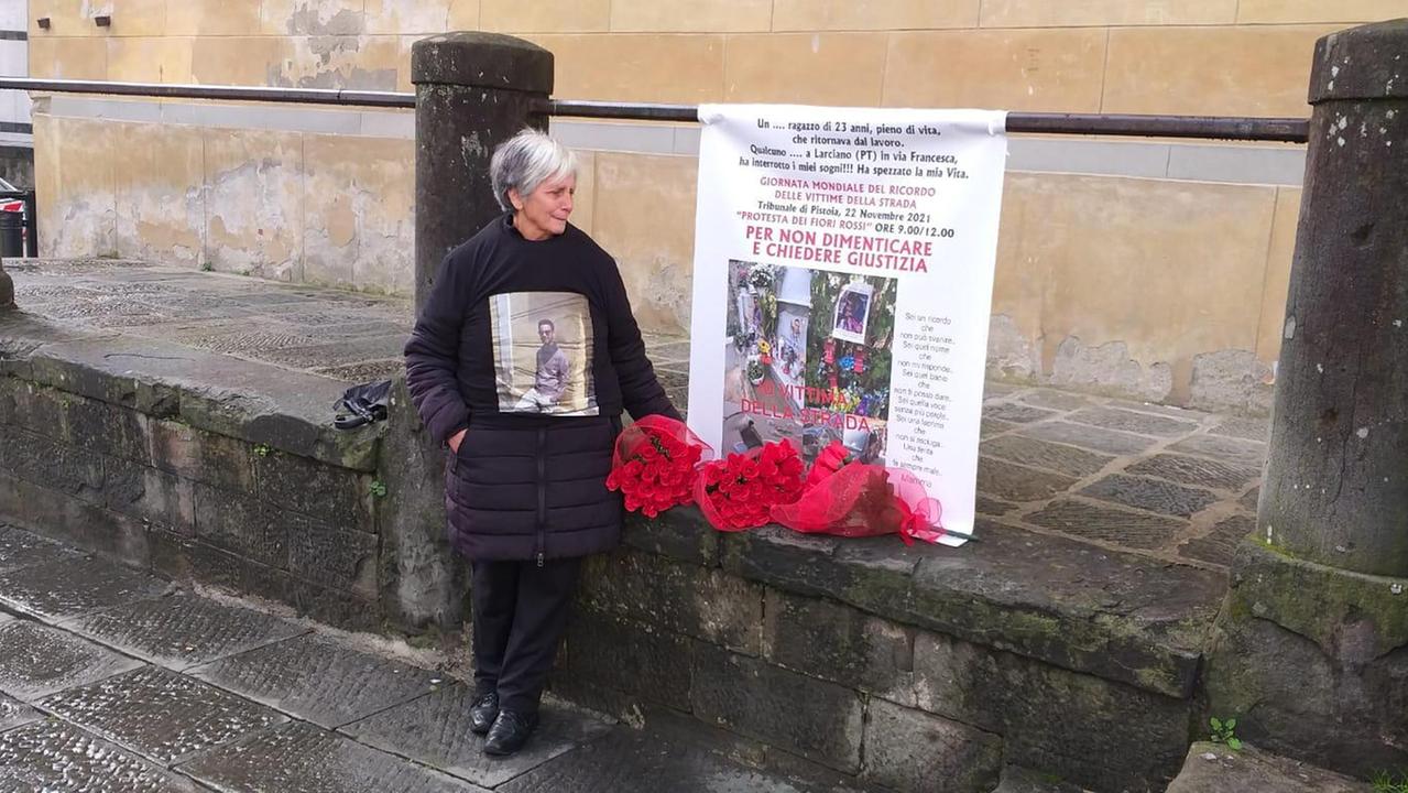 Flora Spanò davanti al tribunale di Pistoia con un cartellone di protesta e i fiori rossi